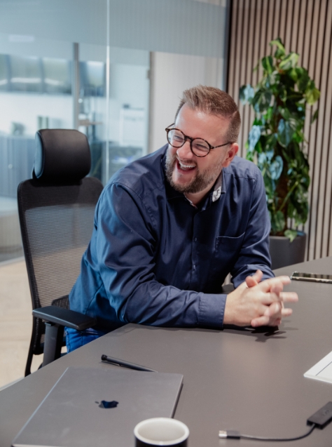 Herr mit Brille am Lachen im Konferenzraum