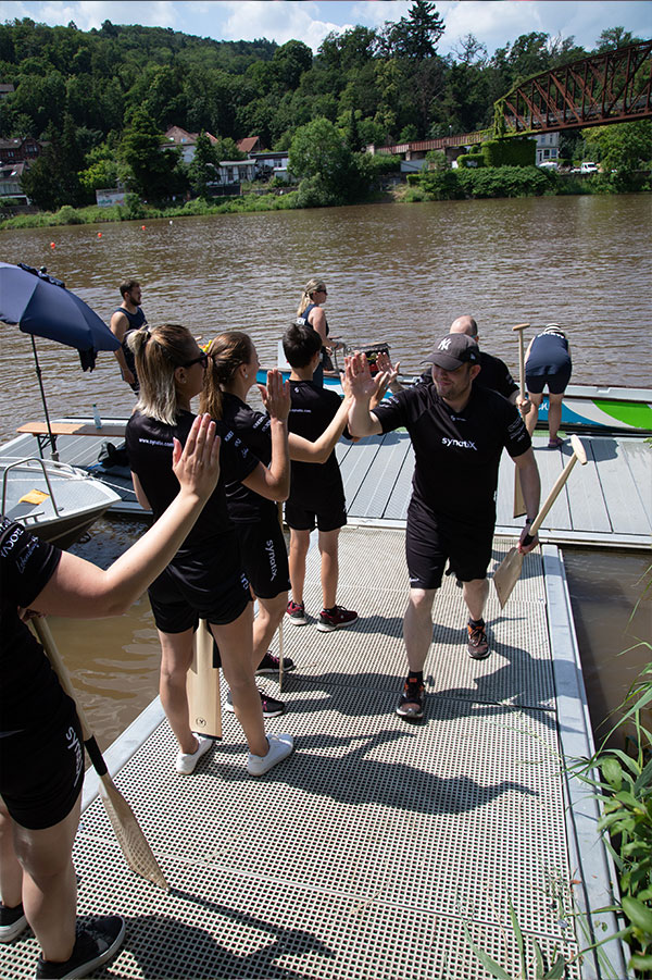 Dragon boat team high-fives on the pier