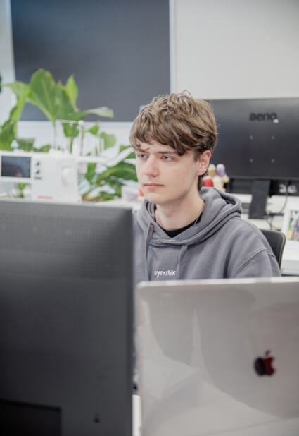 Lerne uns bei einem Praktikum kennen Junger Mann sitzt vor zwei Monitoren
