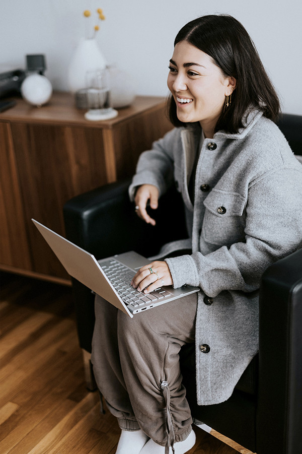 Friendly smiling woman in conversation with laptop on her lap in an armchair