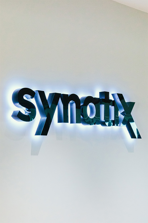Was uns ausmacht Leuchtende Synatix Schrift an der Wand